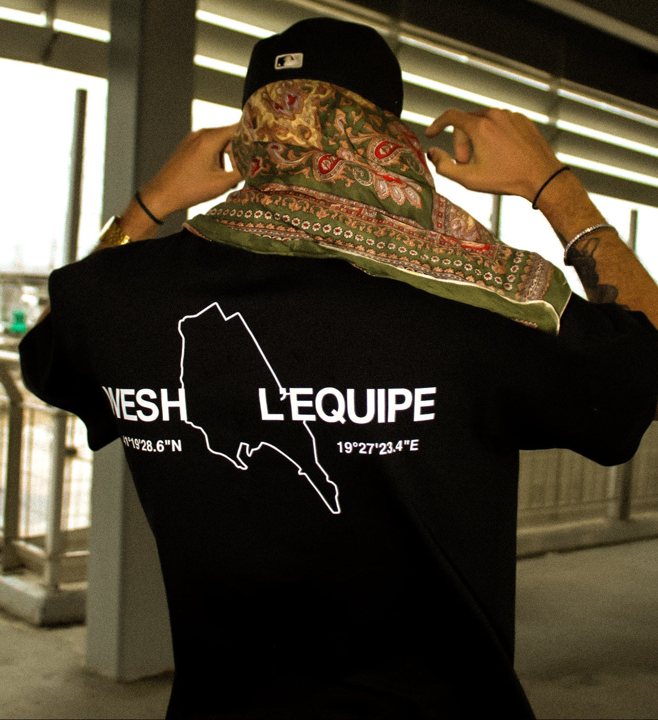 Model wearing a black tshirt with 'Wesh L'Equipe' print